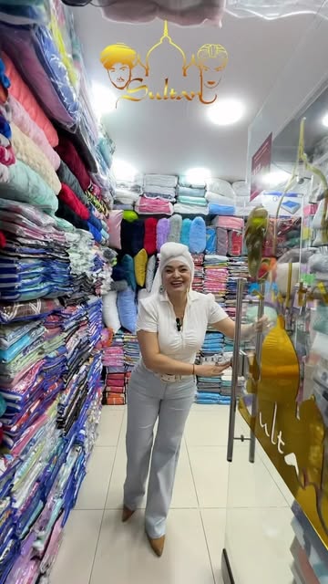 Interior de la tienda con estantes llenos de sábanas de colores